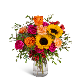 Bouquet of sunflowers, roses, and carnations in a clear glass vase