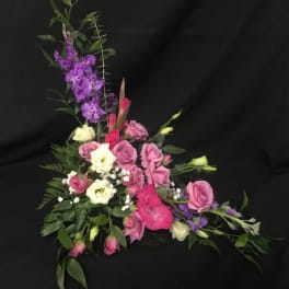 Pink and white floral arrangement with purple flowers on a black background