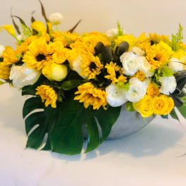 Yellow and white floral arrangement in a low gray bowl