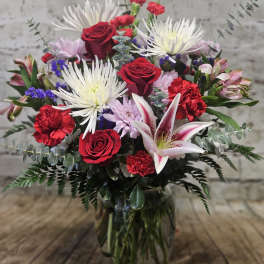 Mixed bouquet with red roses, white lilies, and pink flowers in a glass vase