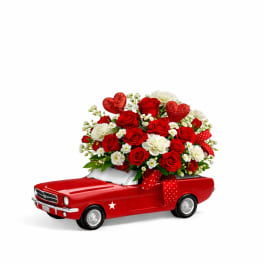 Red rose bouquet in a red toy car with heart decorations