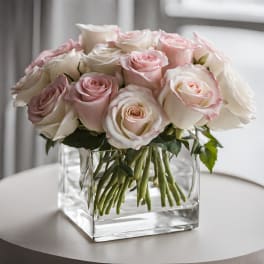 Blush and white roses arranged in a clear square vase