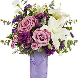 Pink roses and white lilies in a purple glass vase