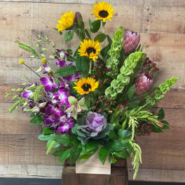 Mixed bouquet with sunflowers, purple orchids, and green blooms in a wooden box