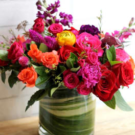 Mixed bouquet of roses and bright flowers in a glass vase