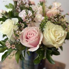 Pastel roses and ruffled blooms arranged in a striped vase
