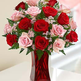 Red and pink roses arranged in a red glass vase