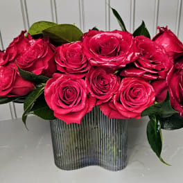 Bright pink roses arranged in a ribbed glass vase