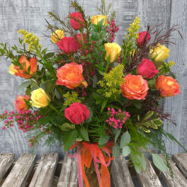 Mixed bouquet of red, yellow, and orange roses in a glass vase