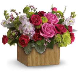Low arrangement of pink and red roses with green accents in a rectangular wooden box