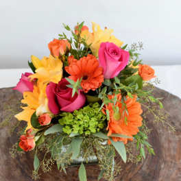 Bright mixed bouquet with pink roses, orange gerberas, and yellow lilies in a low vase