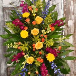 Tall standing spray with yellow, orange, magenta, and blue flowers