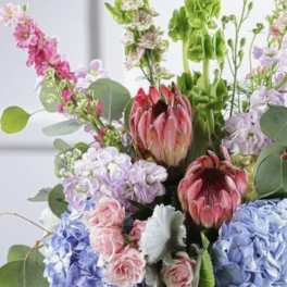 Mixed bouquet with protea, hydrangeas, roses, and tall green blooms