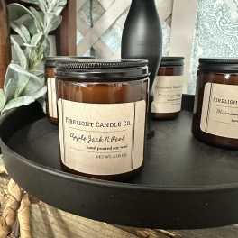 Amber jar candles on a black tray with a lamp and decor