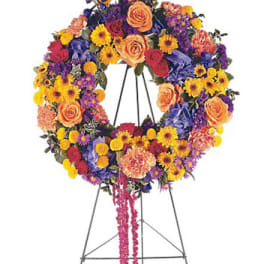Colorful standing wreath of roses, carnations, and daisies on a metal easel stand