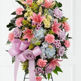 Standing floral spray with pink lilies, roses, hydrangeas, and a lavender ribbon