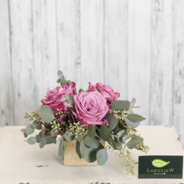 Pink roses in a small square vase with eucalyptus