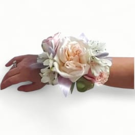 Pastel wrist corsage with peach rose, white alstroemeria, and ribbon on a person's wrist