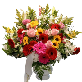 Mixed bouquet of gerbera daisies, roses, and lilies in a white vase