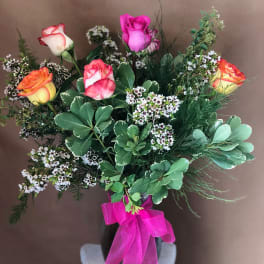 Bouquet of multicolored roses in a black vase with a pink ribbon