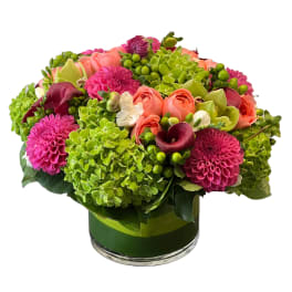 Bright mixed bouquet in a glass vase with pink, coral, and green blooms