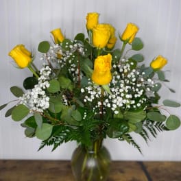 Yellow roses in a glass vase with white baby's breath