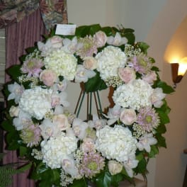 Large floral wreath on an easel with white and pale pink flowers