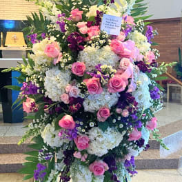 Large standing floral spray with pink roses, white hydrangeas, and purple flowers