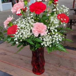 Pink and red carnations in a red glass vase