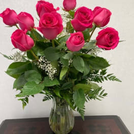 Pink roses arranged in a clear glass vase with greenery