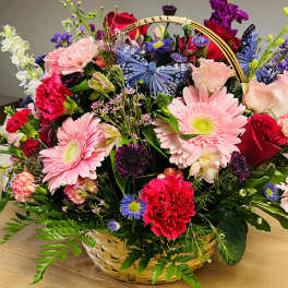 Mixed flower basket with pink gerberas, roses, carnations, and butterflies