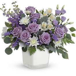 Lavender roses and white flowers in a clear square vase