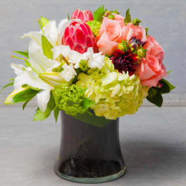 Pink roses and white lilies arranged in a dark glass vase