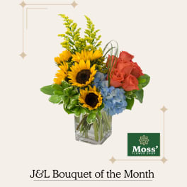 Bouquet of sunflowers, coral roses, and blue hydrangeas in a glass vase