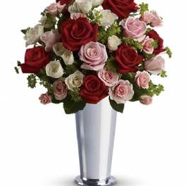 Red, pink, and white roses arranged in a tall silver vase
