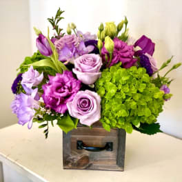 Purple and green floral arrangement in a wooden box
