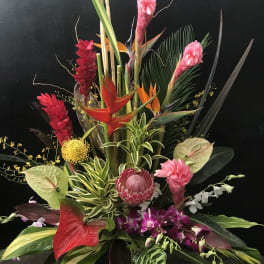 Tropical floral arrangement with pink ginger, red anthuriums, and orchids
