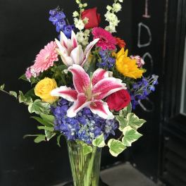 Mixed bouquet in a clear glass vase with lilies, roses, hydrangea, and gerbera daisies