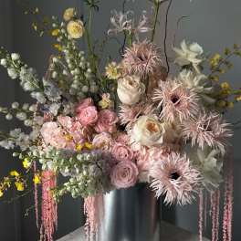 Tall pastel floral arrangement in a silver cylinder vase