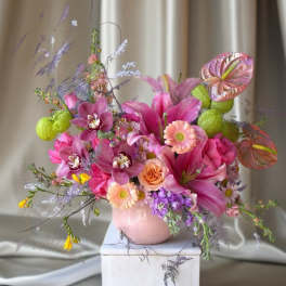 Pink and purple floral arrangement in a pale pink vase