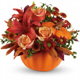 Autumn floral arrangement in a pumpkin container with roses, lilies, and mums
