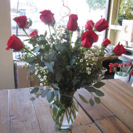 Red roses in a clear glass vase with white filler flowers