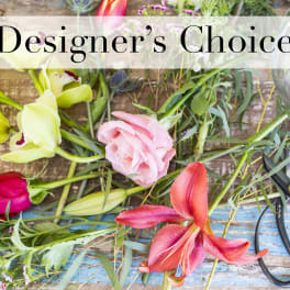 Loose flowers and scissors on a wooden surface with a "Designer’s Choice" sign