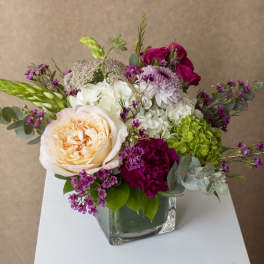 Mixed bouquet in a square glass vase with peach, white, and magenta blooms