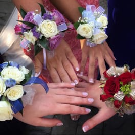 Hands wearing rose corsages in red, white, blue, and lavender