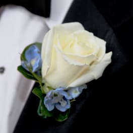 White rose boutonniere with small blue flowers on a black suit lapel