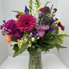 Colorful mixed bouquet in a clear glass vase with gerbera daisies and snapdragons