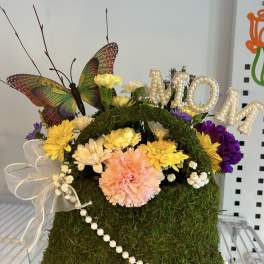 Moss-covered floral handbag with mixed flowers, butterfly, and pearl trim