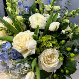 Bouquet of white roses, blue flowers, and green accents