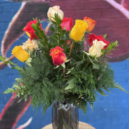 Mixed roses in a tall glass vase with greenery